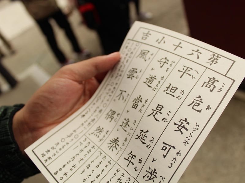 A hand holding a Japanese Omikuji fortune paper at Sensoji Temple