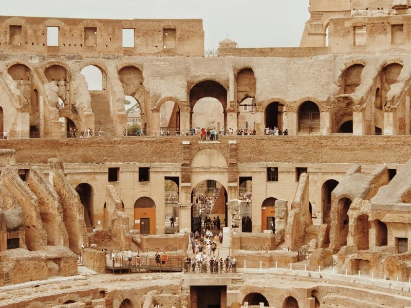 Inside view of the Colosseum with tourists exploring the ancient structure from ground to top levels.